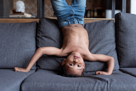 kid standing upside down on sofaの写真素材