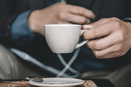 cropped shot of businessman holding cup of coffee in hand in cafeの写真素材