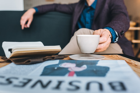 partial view of businessman in suit resting on sofa in cafeの写真素材