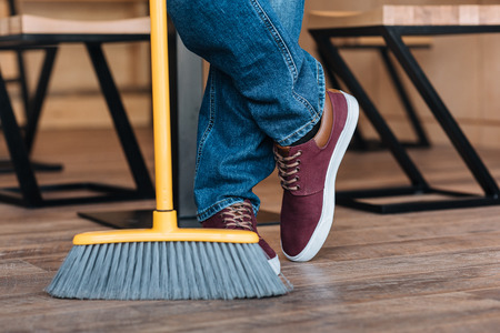partial view of worker legs and broom in coffee shopの写真素材