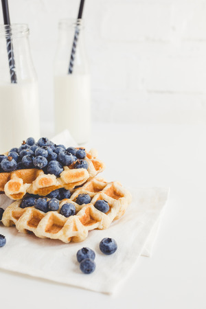 breakfast of freshly baked waffles with blueberries and milkの写真素材