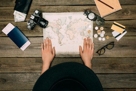 Top view of tourist in a black hat sitting and looking at map, planning travelの写真素材