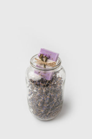 close-up shot of handcrafted soap in jar with lavender flowers on white surfaceの写真素材