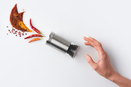 top view of woman reaching for pepper grinder with beautiful spices composition isolated on whiteの写真素材
