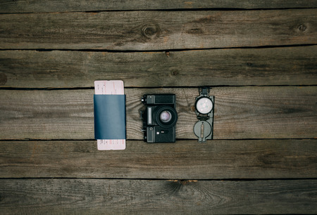 Passport with ticket and film camera with compass on a wooden surface. travel concept