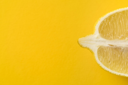 Cut ripe lemon isolated on yellowの写真素材
