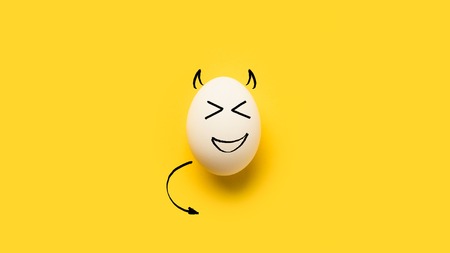 painted egg with devil isolated on yellow  の写真素材