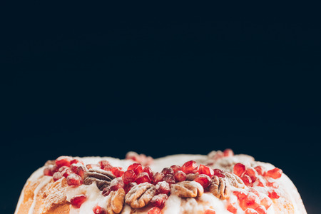 close up of traditional homemade christmas cake with pomegranate and pecan nuts, isolated on blackの写真素材