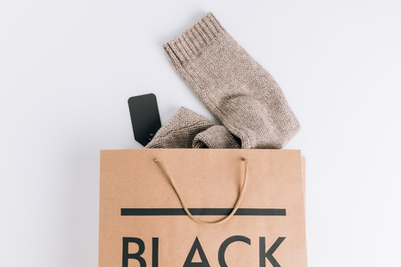 paper bag with sweater inside and black sign on white surface