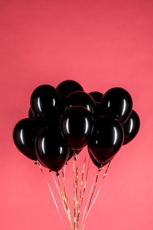 pack of glossy black balloons isolated on redの写真素材