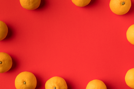 top view of frame made from fresh tangerines isolated on redの写真素材