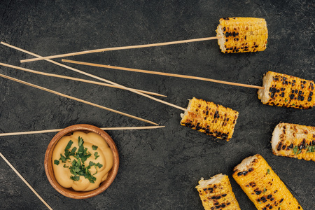 top view of grilled corn pierced with sticks and sauceの写真素材
