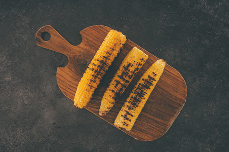 top view of grilled corn on wooden cutting board in rowの写真素材