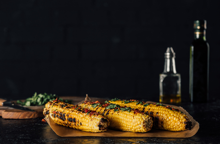 grilled corncobs with spices isolated on blackの写真素材