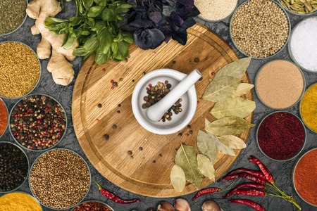 Top view of Mortar and pestle for grinding pepper on a wooden board among spicesの写真素材