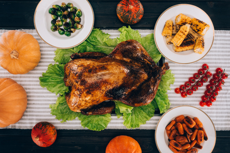 Baked turkey in the middle of the black wooden served table for thanksgiving dayの写真素材
