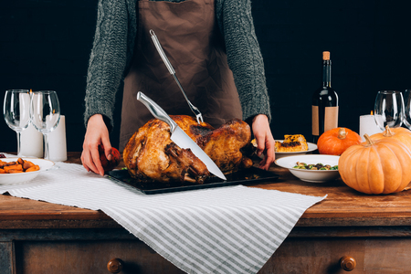 Cook standing near baked turkey and served table on thanksgiving dayの写真素材