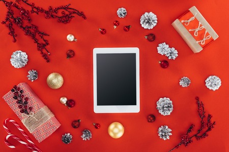 top view of digital tablet with copy space, christmas decor and presents, isolated on red