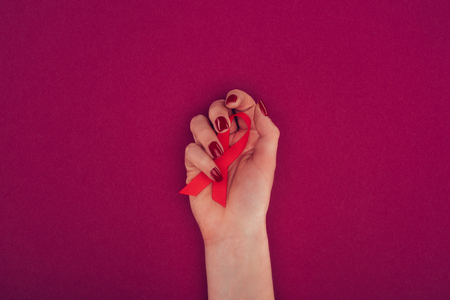 cropped view of hand with red aids ribbon, isolated on pinkの写真素材