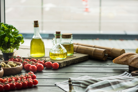 olive oil bottles with vegetables on wooden tableの写真素材