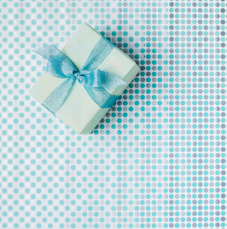 top view of christmas gift box with ribbon on patterned wrapping paperの写真素材