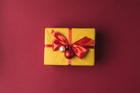 top view of festive decorated christmas gift with ribbon on red tabletopの写真素材