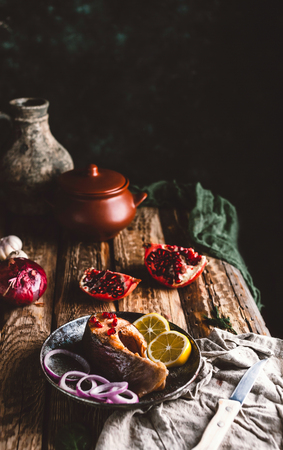Baked salmon steak with lemon and onion on plate with pomegranateの写真素材