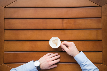 man sitting at table with cup of coffeeの写真素材