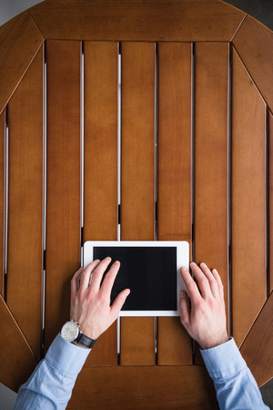 man using tablet and sitting at table