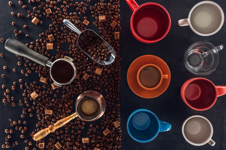 roasted coffee beans, scoop, coffee pot, coffee tamper and cup of coffee with empty cups on blackの写真素材
