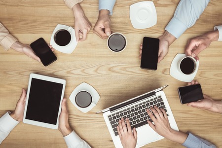 businesspeople on brainstorming with documents and laptop, smartphones, digital tablet and coffee at...