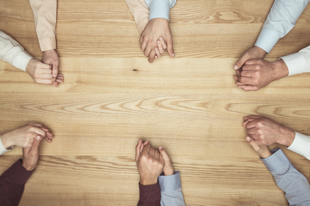 people holding hands on wooden tabletopの写真素材