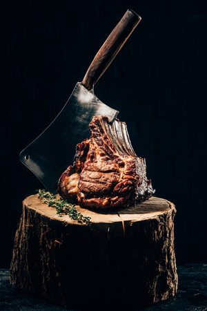 delicious grilled ribs with meat knife and rosemary on wooden stumpの写真素材