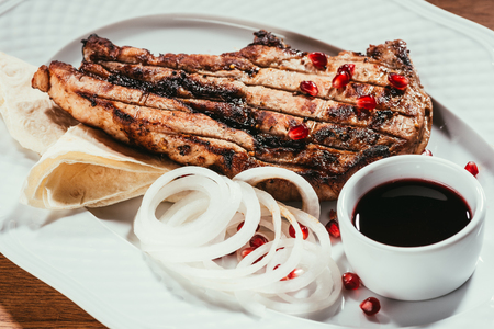 grilled steak on plate with onion rings and saucerの写真素材