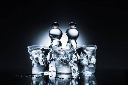 crumpled plastic bottles and cups with waterの写真素材