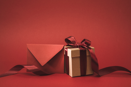 close up view of empty envelope and present with ribbon isolated on redの写真素材
