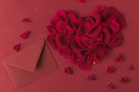 top view of heart made of roses petals and envelope isolated on red, st valentines day conceptの写真素材
