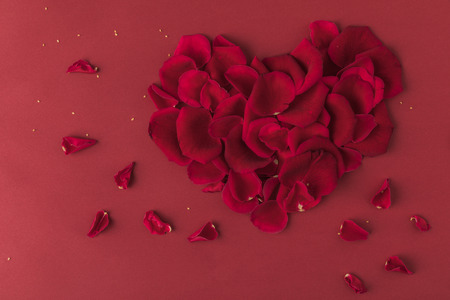 top view of heart made of roses petals isolated on redの写真素材
