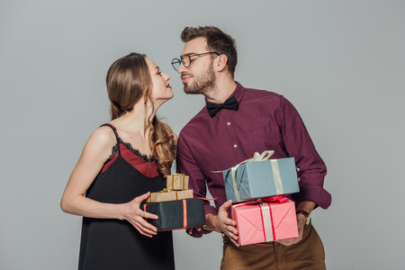fashionable happy young couple holding gift boxes and able to kissの写真素材