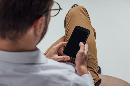cropped shot of young man in eyeglasses using smartphone with blank screenの写真素材