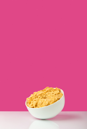 white bowl full of healthy tasty corn flakes on pinkの写真素材