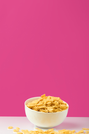 white bowl full of sweet tasty corn flakes on pinkの写真素材