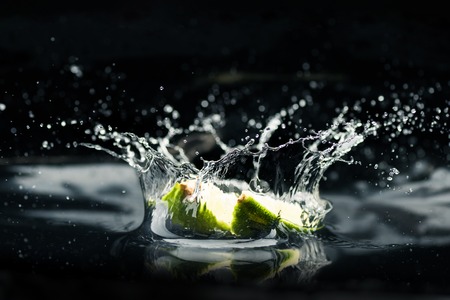 slices of lime falling in waterの写真素材