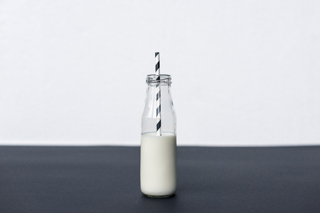 glass bottle with milk and striped drinking strawの写真素材