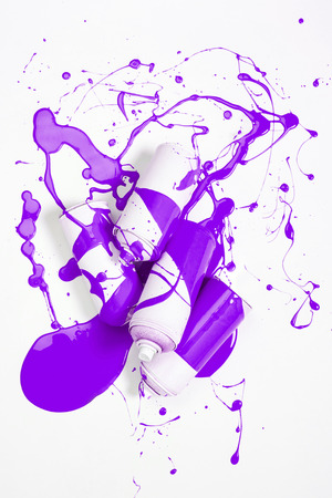close up view of spray paint in cans covered with purple paintの写真素材