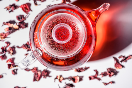 top view of transparent glass teapot with hibiscus tea and scattered tea