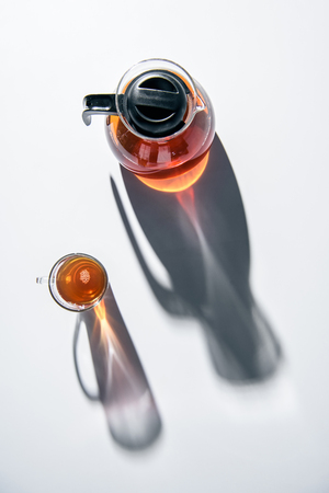 transparent teapot and glass cup with tea on white tableの写真素材