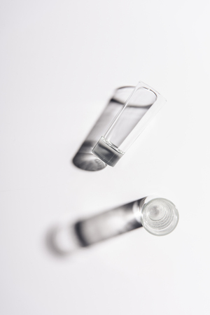 one glass with water and one empty glass on white surfaceの写真素材