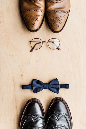 shoes, glasses and tie bow on wooden surfaceの写真素材