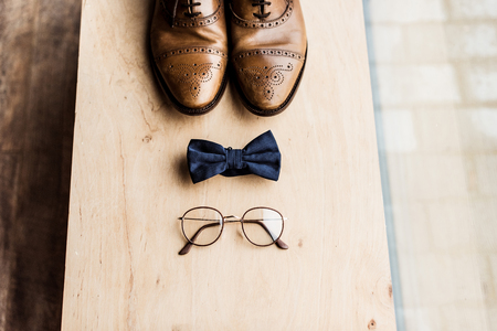 Shoes, tie bow and glasses on wooden standの写真素材